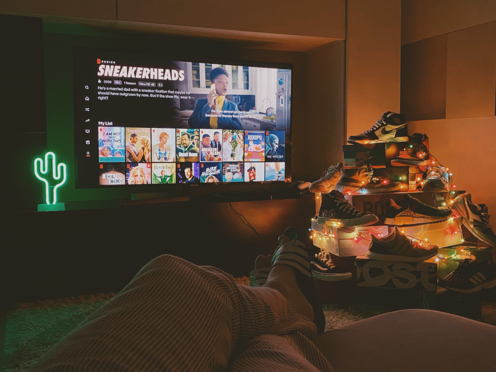 Man watching Netflix in a sneaker-themed bedroom man cave