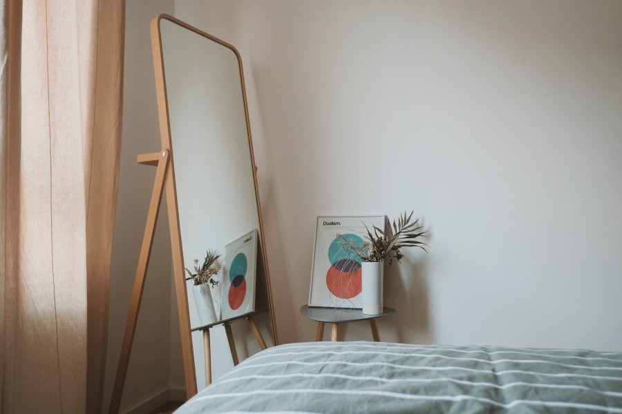A full-height mirror next to a bed