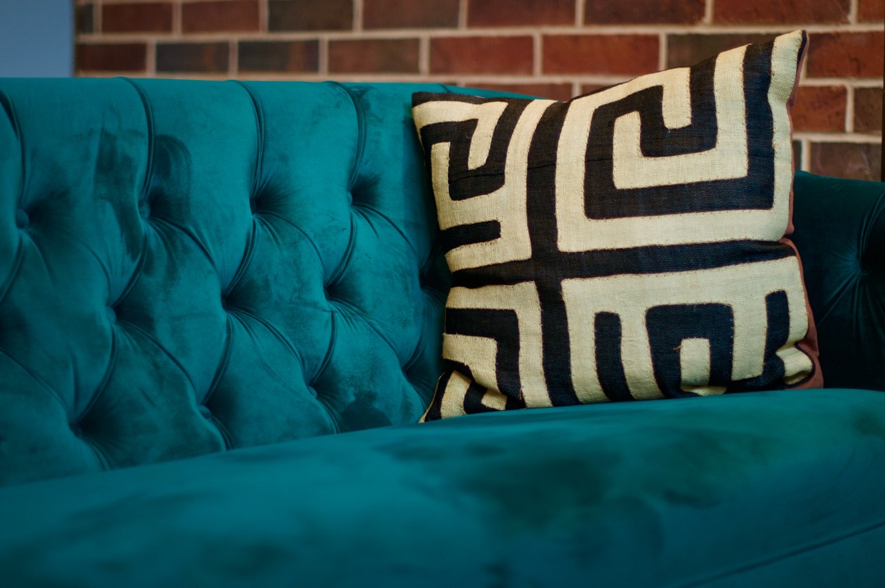 Cosy turquoise suede sofa with a patterned cushion