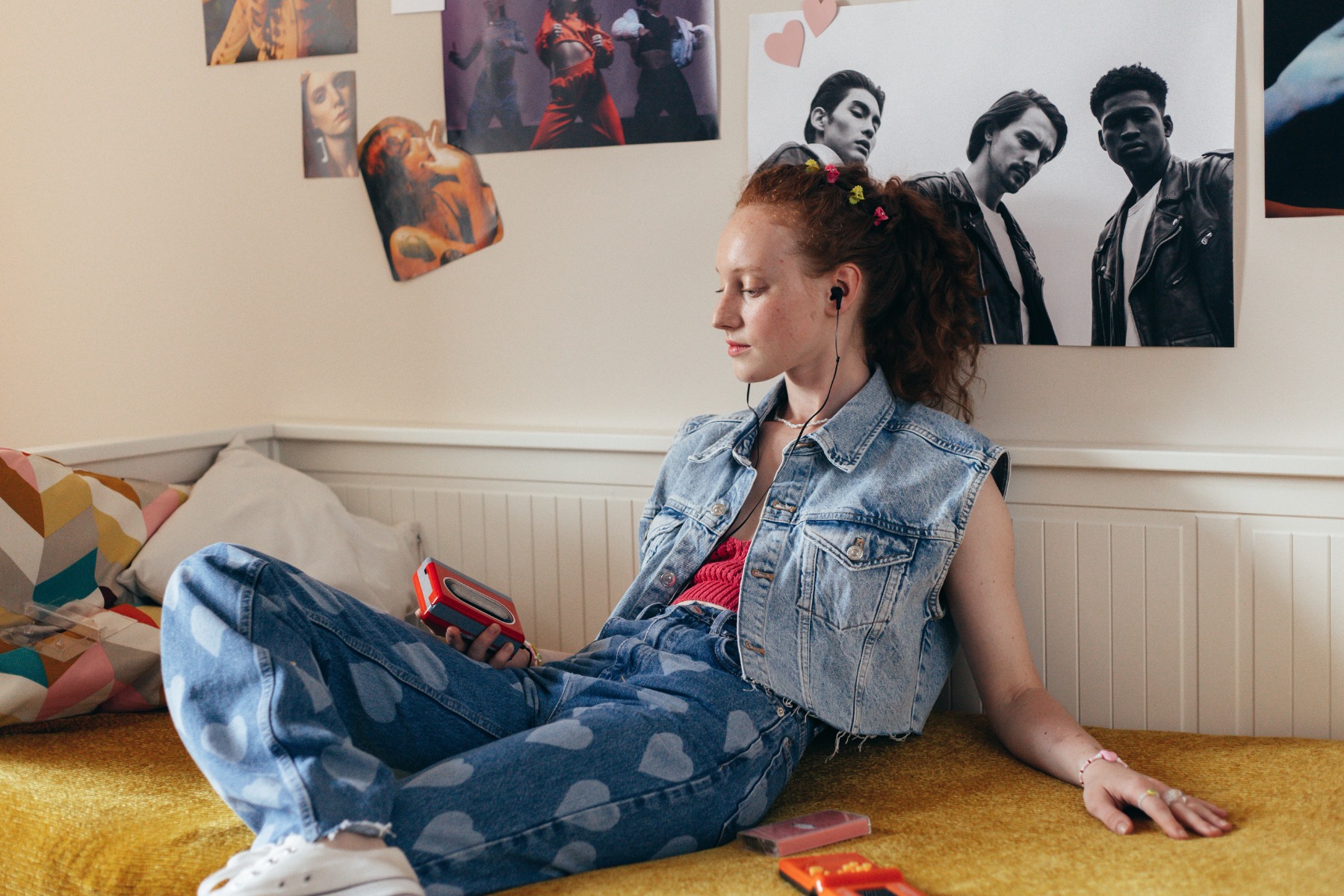 A teenager sitting on a bed listening to music